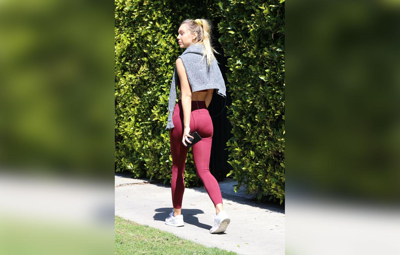 Alexis Ren wears a matching set of maroon workout top and leggings for a  Pilates session