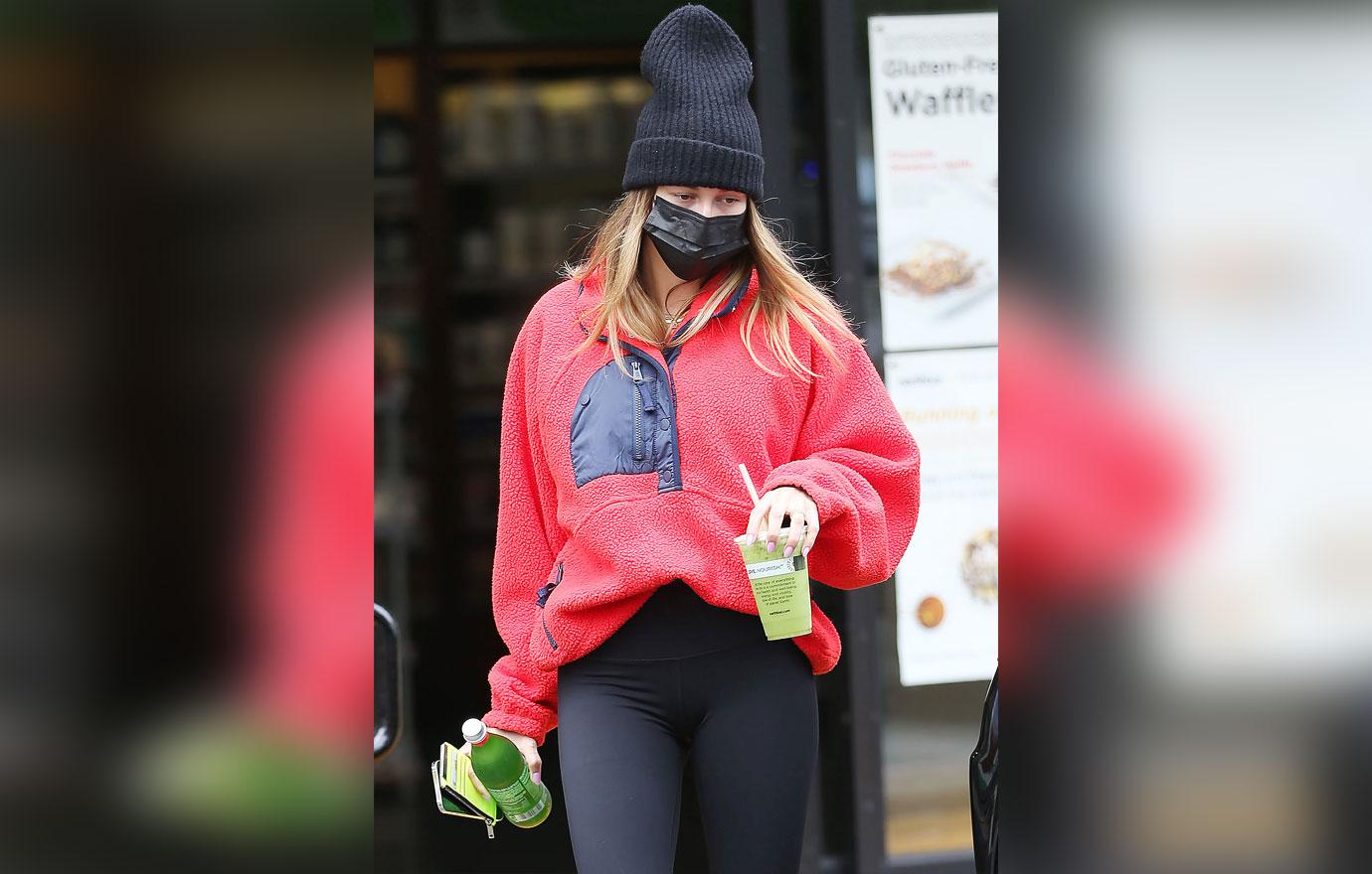 Hailey Bieber sports red sweater and black leggings while grabbing a  post-workout juice at Earth