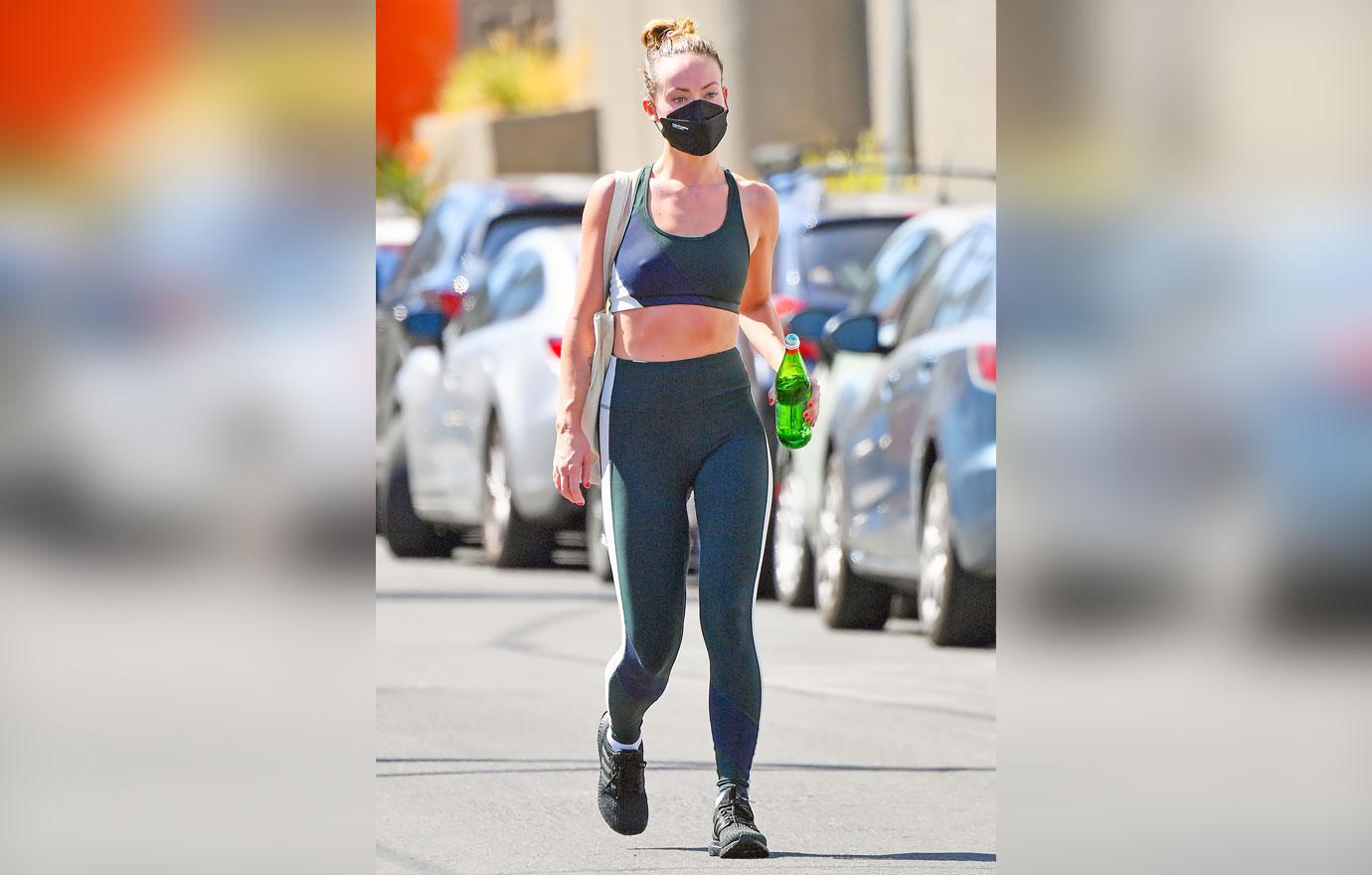 Olivia Wilde wears a teal-green sports bra and leggings with a