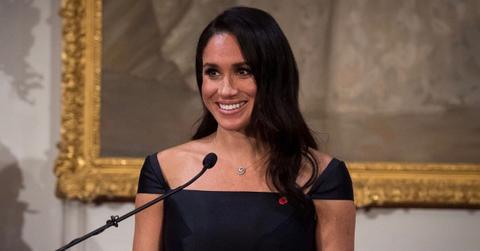 Meghan Markle speaking at an event in a black dress