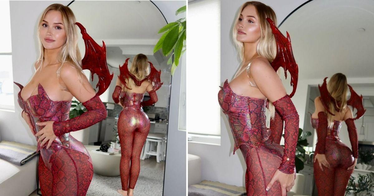 Tana Rain stands in front of a mirror in a red snakeskin dragon outfit with winged details.