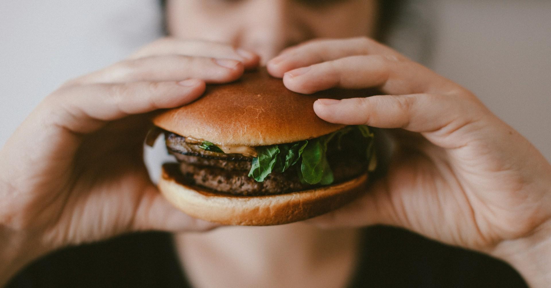 Photo of a person eating a burger. 