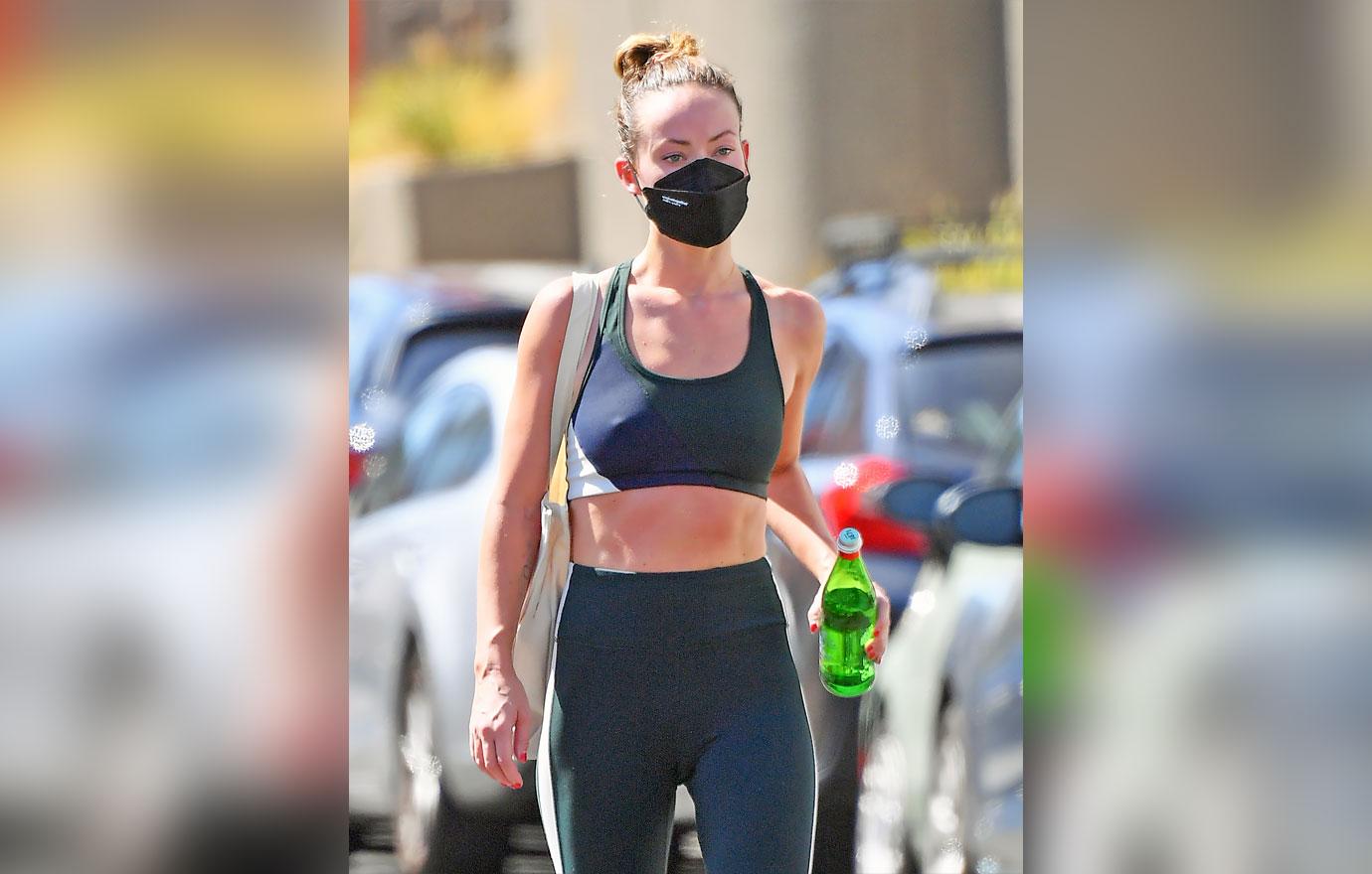 Olivia Wilde wears a teal-green sports bra and leggings with a