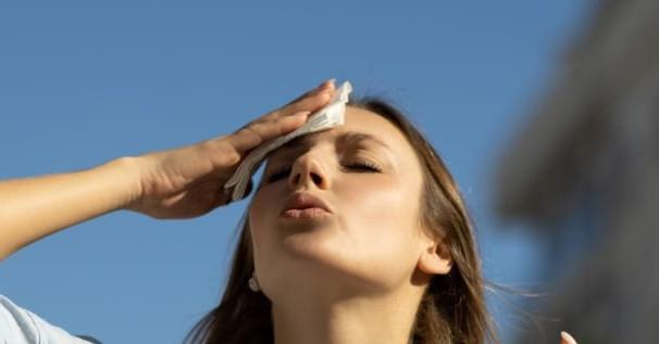 Photo of someone wiping their forehead. 